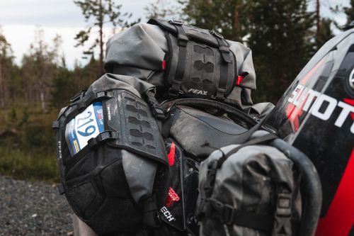 Adventure motorcycle with multiple grey and black soft luggage bags strapped on for travel.